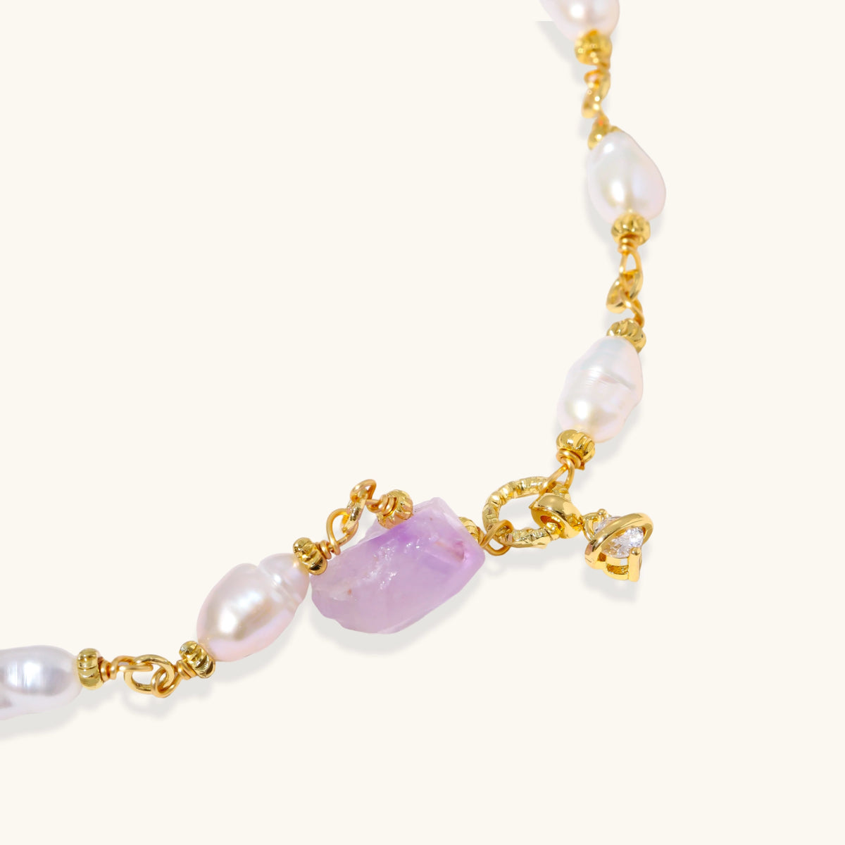 Gold-plated bracelet with lustrous baroque pearls and raw lavender amethyst centerpiece on white background.