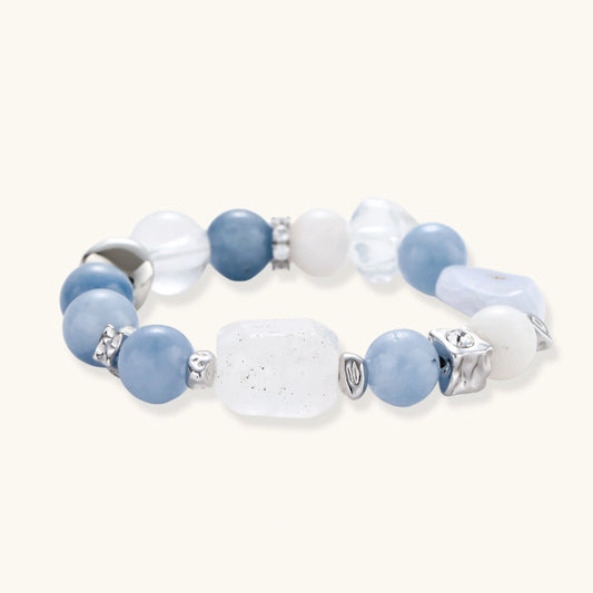 Stretchable bracelet with blue aquamarine beads, clear quartz crystals and copper accents on white background.